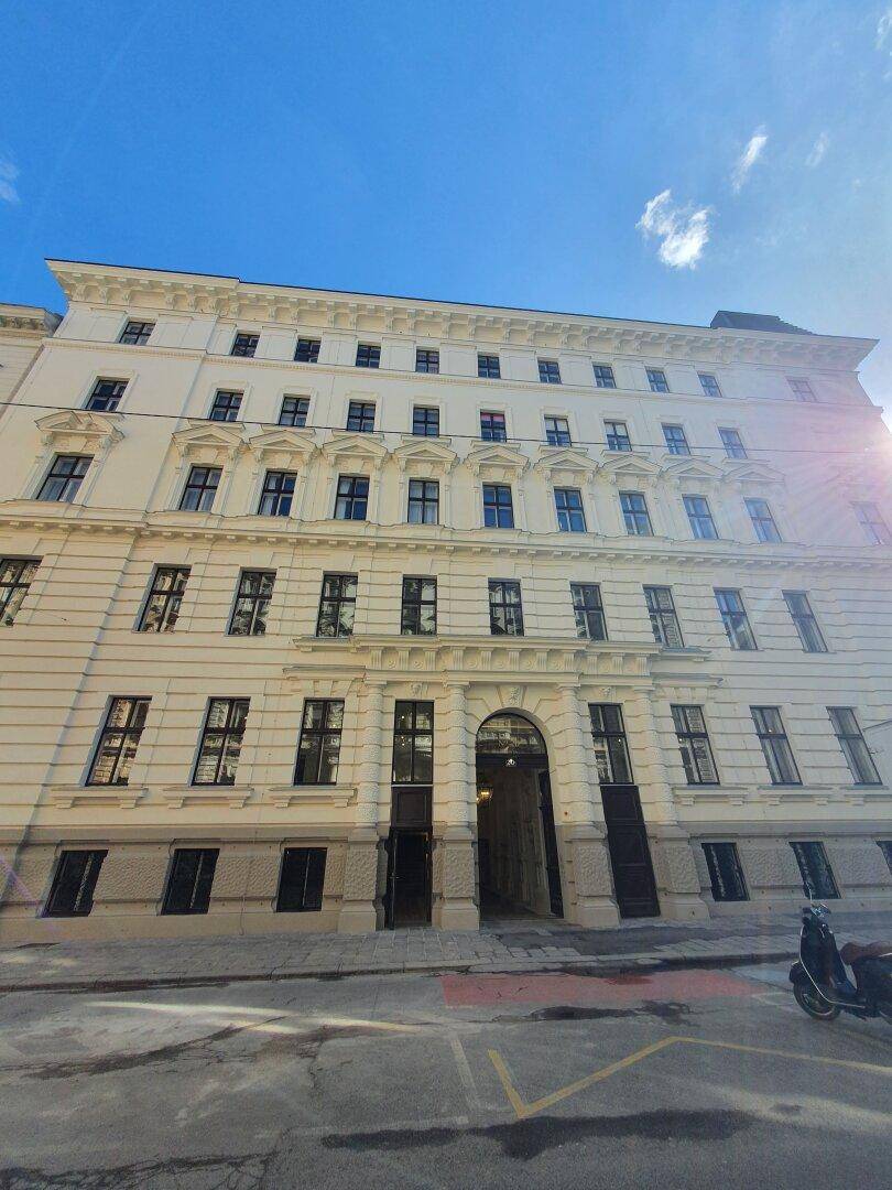 Klassische Fassade eines Mehrfamilienhauses mit vielen Fenstern und historischer Architektur.