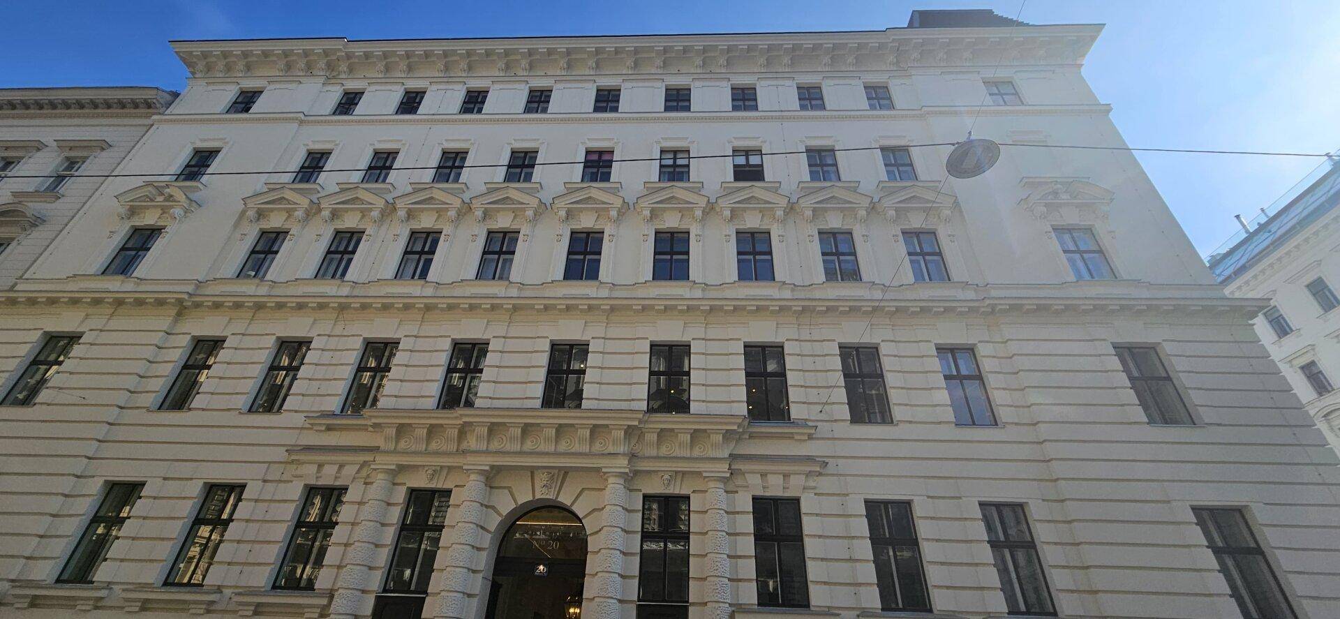 Klassische Fassade eines historischen Gebäudes mit vielen Fenstern und dekorativen Elementen.