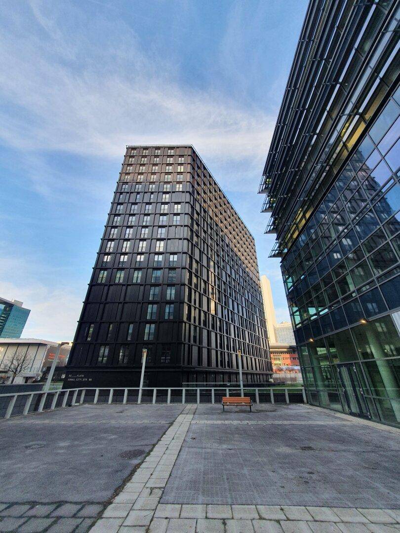 Beeindruckende moderne Hochhäuser mit dunkler und gläserner Fassade unter weitem Himmel.