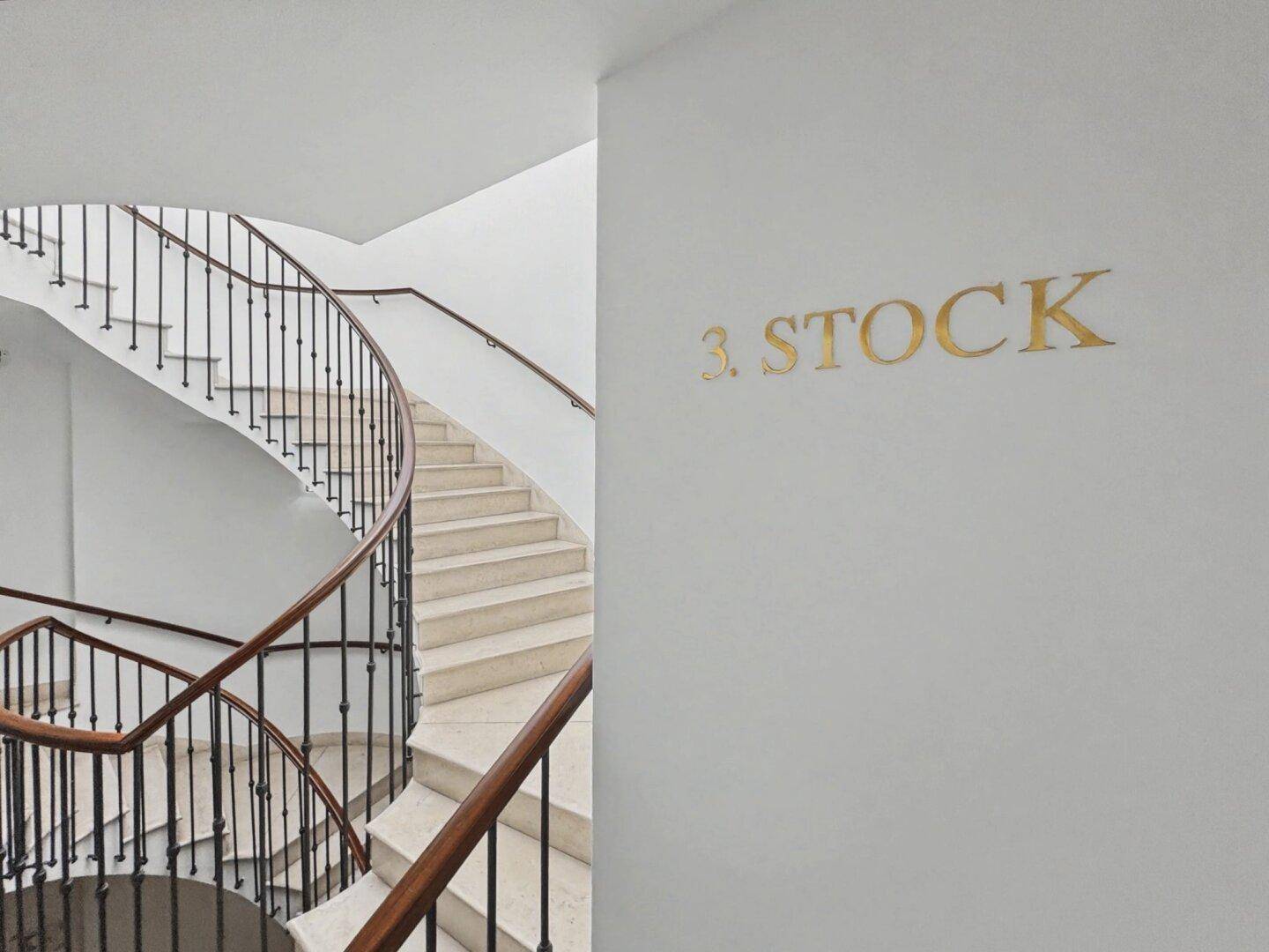 Elegantes Treppenhaus mit geschwungener Marmortreppe und schmiedeeisernem Geländer, führt zum dritten Stock.