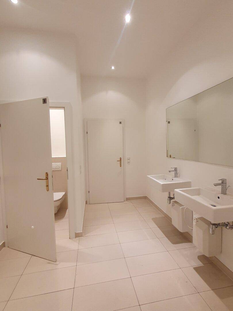 Modernes Badezimmer mit zwei Waschbecken, großem Spiegel und hellem Fliesenboden.