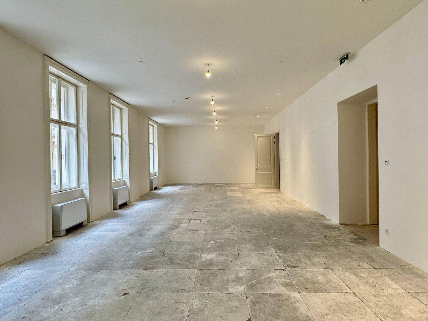 Großer, leerer Raum mit hohen Fenstern und Fliesenboden, bereit für die Einrichtung.