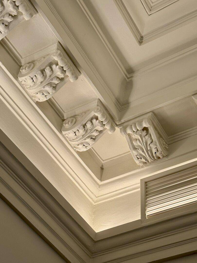 Detailansicht einer aufwendig verzierten Stuckdecke mit klassischen Ornamenten.