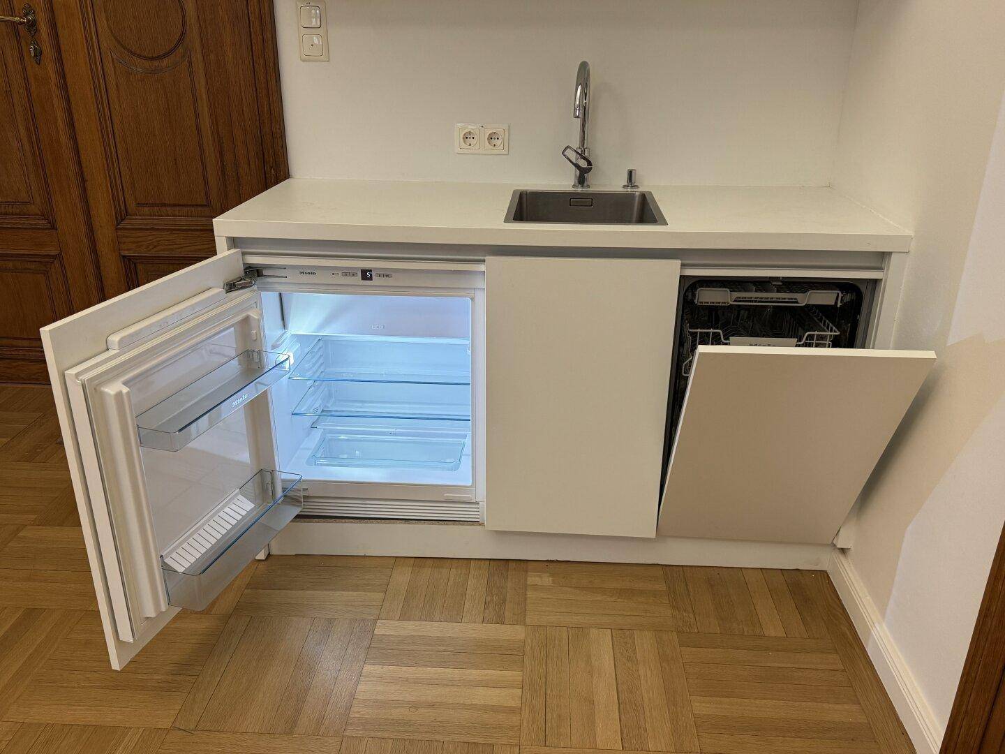 Offene Küchenzeile mit integriertem Kühlschrank und Geschirrspüler, ideal für kleine Räume.