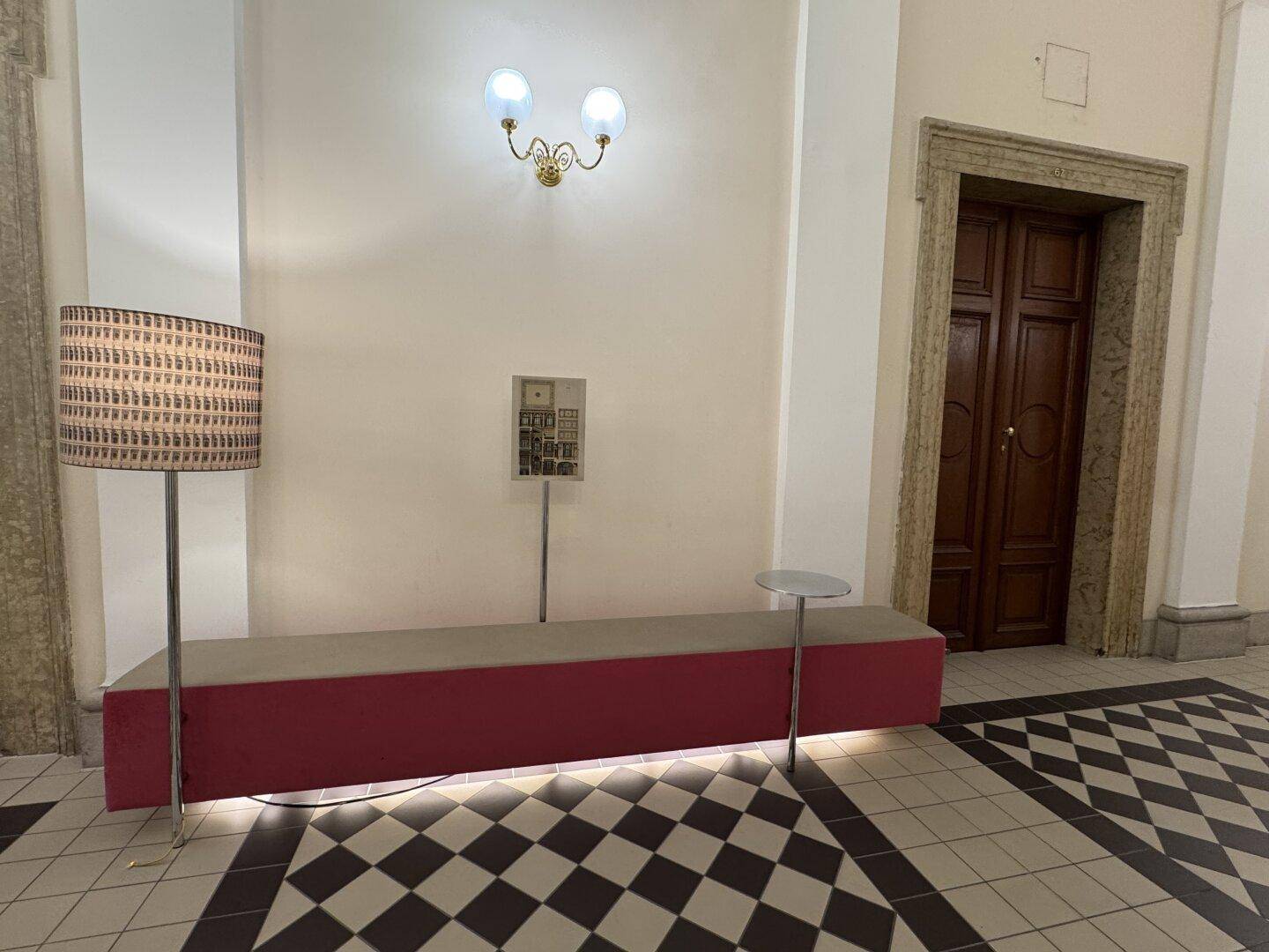 Historischer Eingangsbereich mit Sitzbank, Stehlampe und gemustertem Fliesenboden.