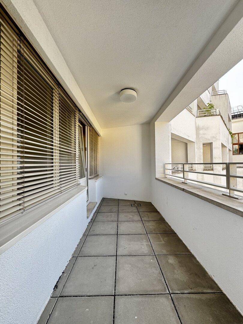 Langer, schmaler Balkon mit Fliesenboden und Metallgeländer, ideal für entspannte Stunden im Freien.