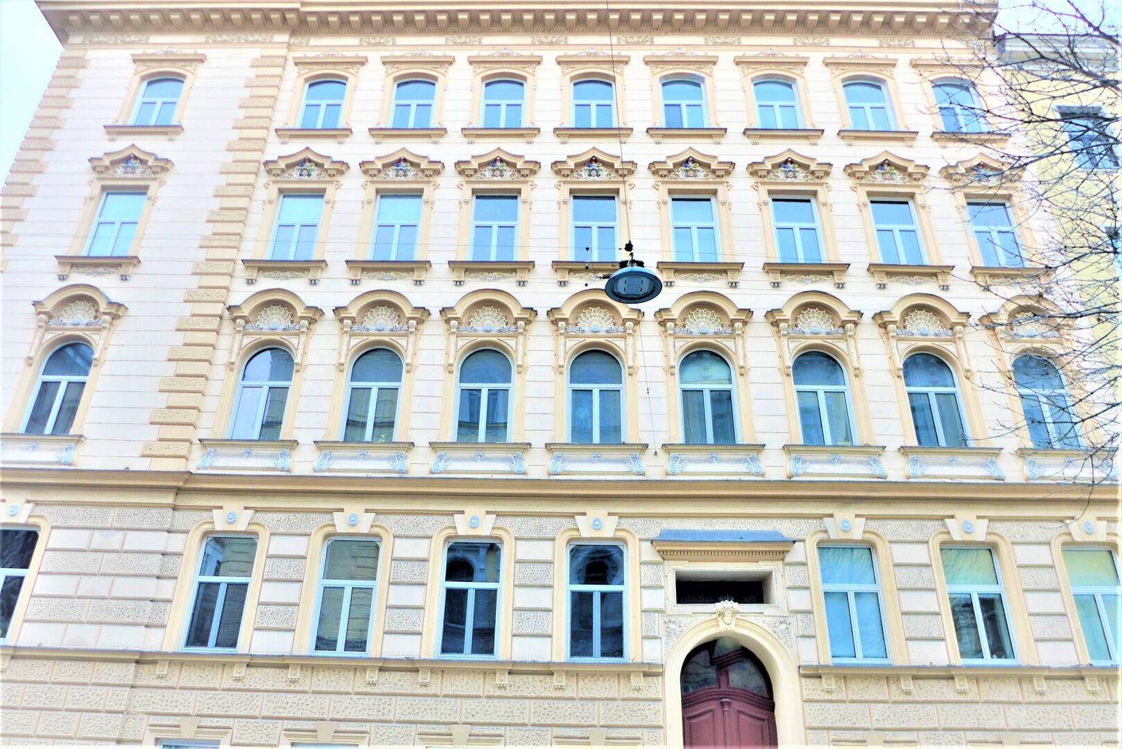 Historische Gebäudefassade mit vielen Fenstern und dekorativen Stuckelementen.