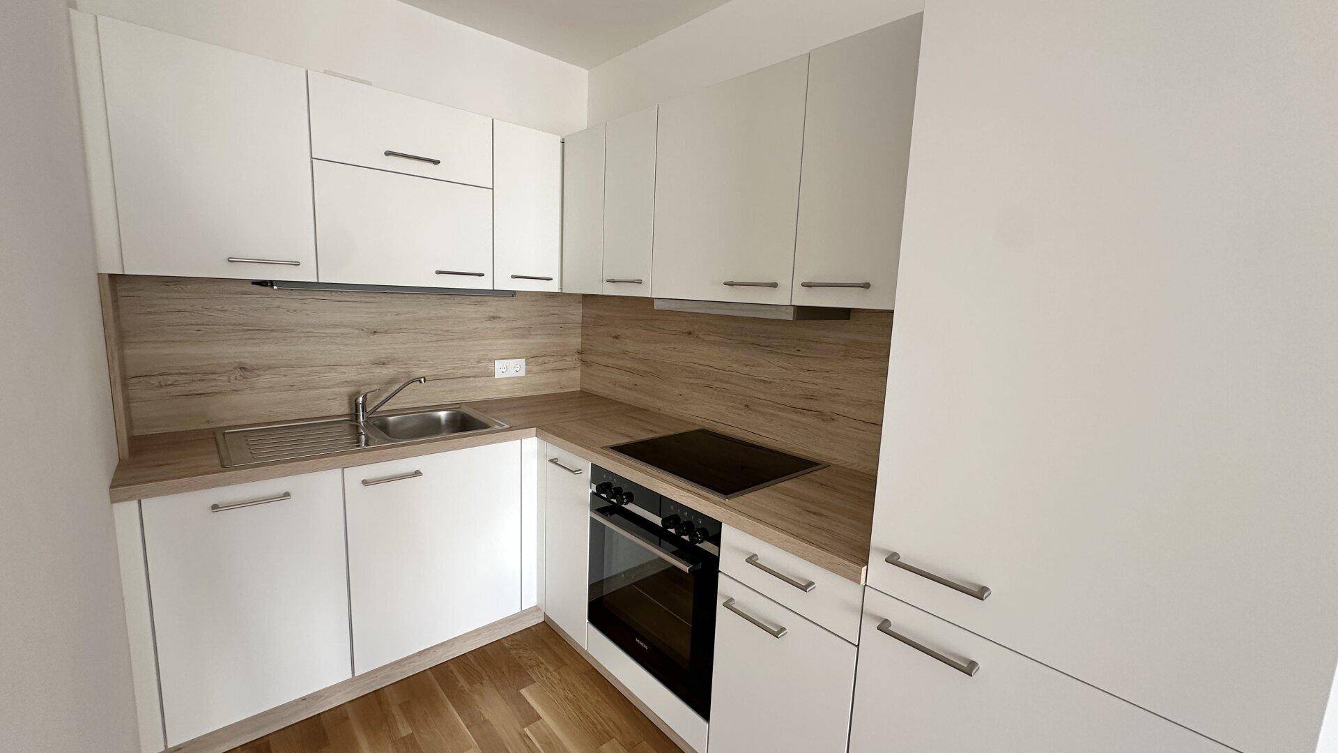 Moderne Einbauküche mit weißen Schränken, Holzoptik-Arbeitsplatte und integrierten Geräten.