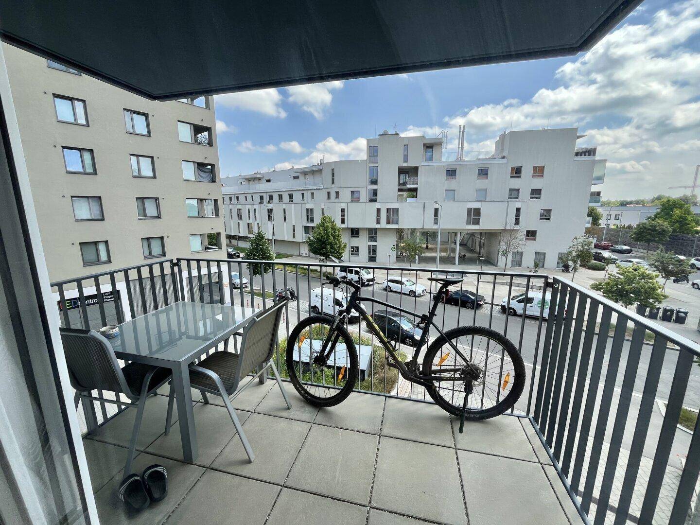 Möblierter Balkon mit Blick auf moderne Wohngebäude und die umliegende Nachbarschaft.