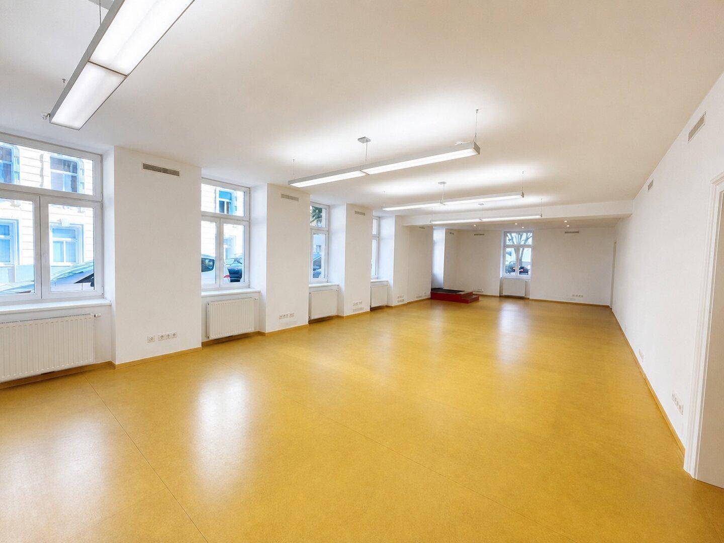 Heller und geräumiger Gewerberaum mit zahlreichen Fenstern und moderner Beleuchtung.