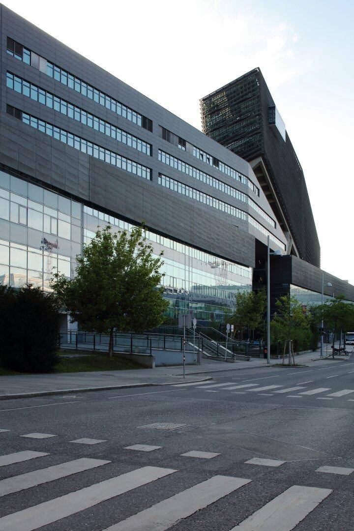 Modernes Bürogebäude mit dunkler Fassade und großen Fensterfronten an einer städtischen Kreuzung.