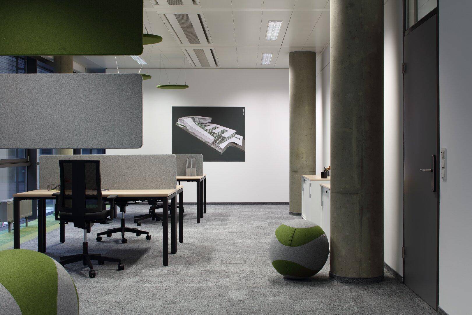 Offener Bürobereich mit Schreibtischen, ergonomischen Stühlen und schallabsorbierenden Paneelen an der Decke.