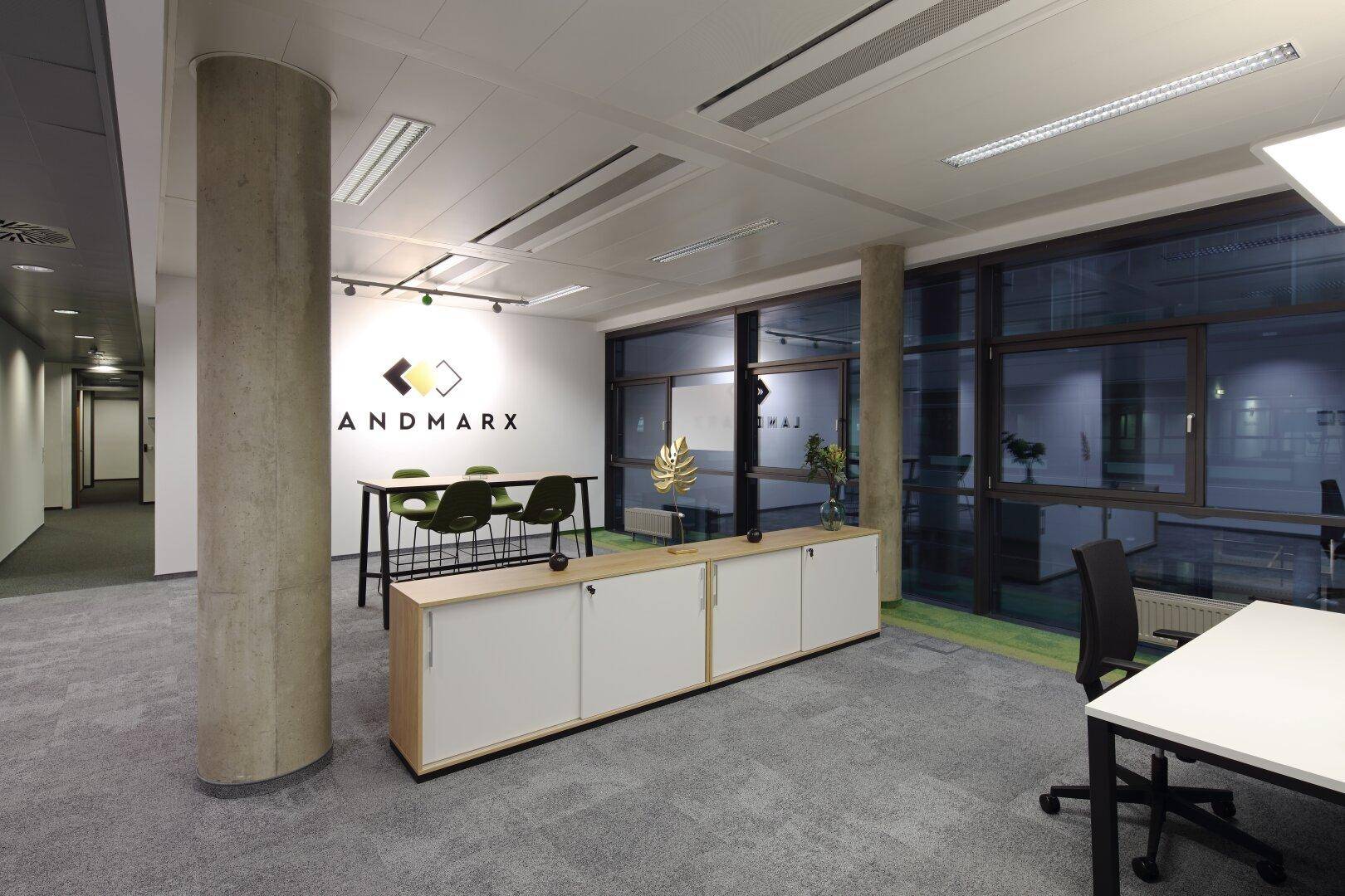 Modernes Büro mit Teppichboden, großen Fenstern und einer langen Theke mit Barhockern.