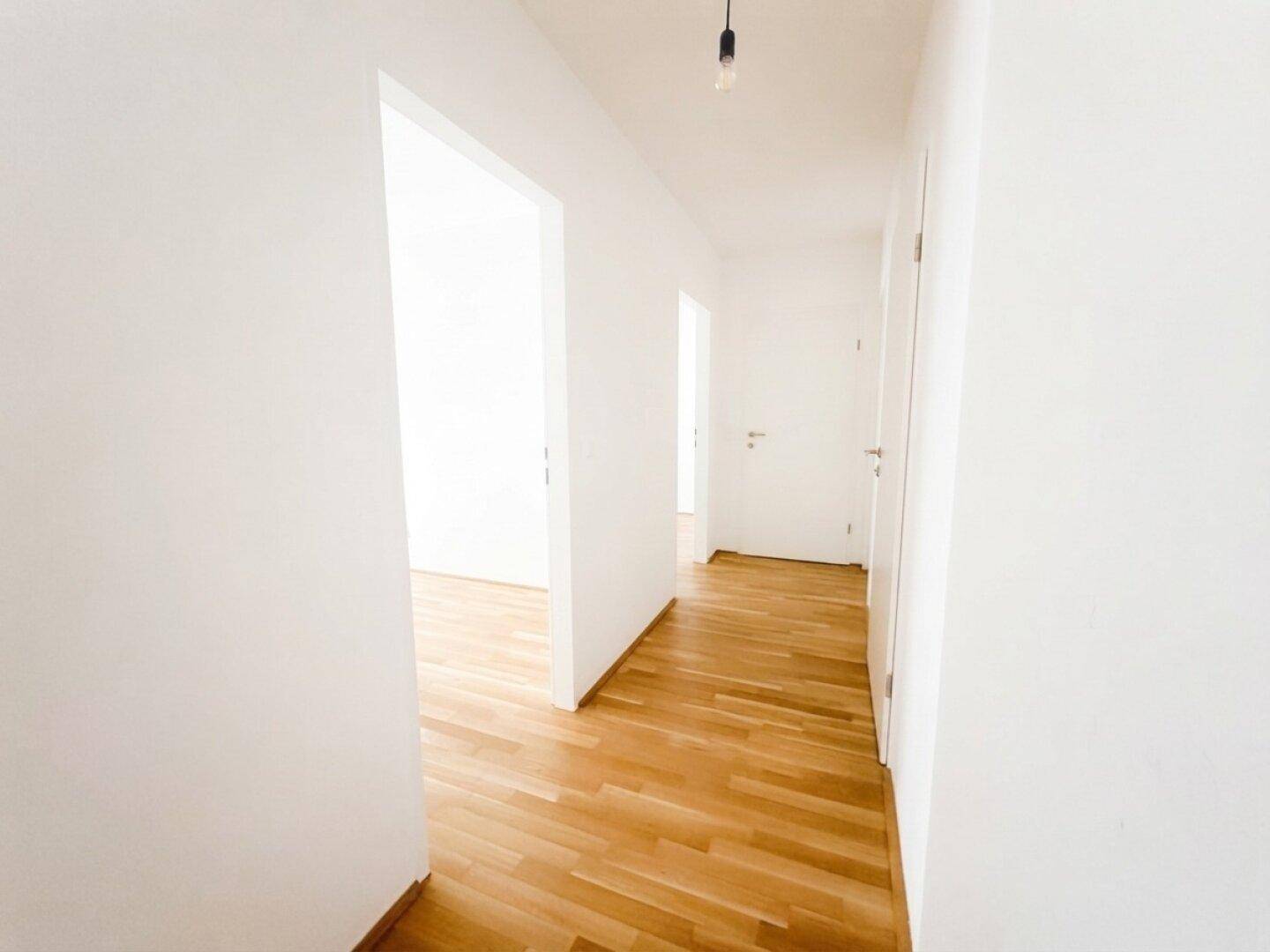 Heller Flur mit Parkettboden, der zu verschiedenen Zimmern der Wohnung führt.