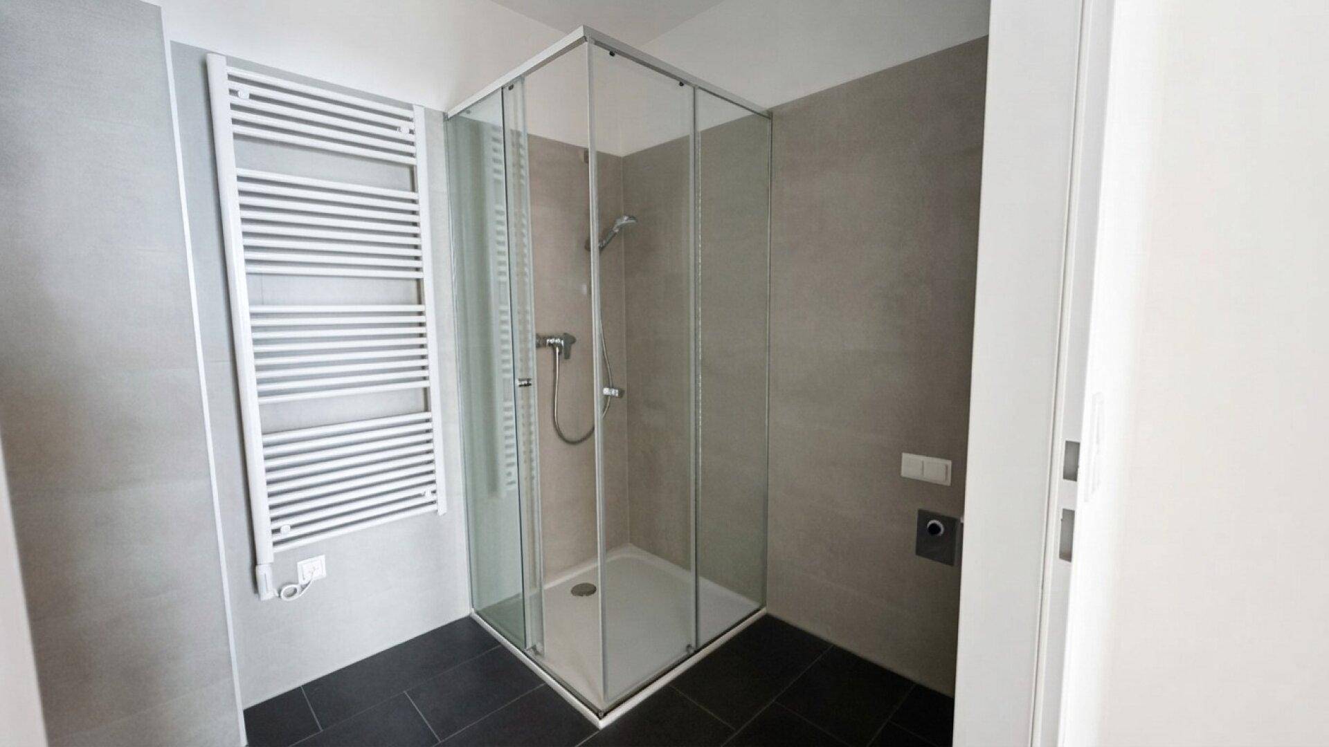 Modernes Badezimmer mit Duschkabine aus Glas und praktischem Handtuchheizkörper.