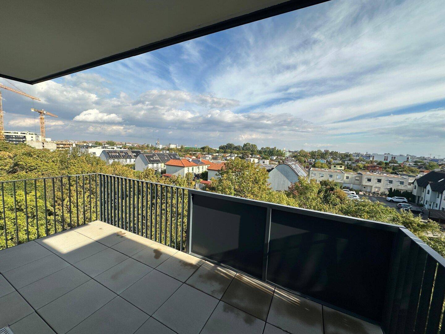 Geräumiger Balkon mit Fliesenboden und weitem Blick über die Stadt und grüne Umgebung.