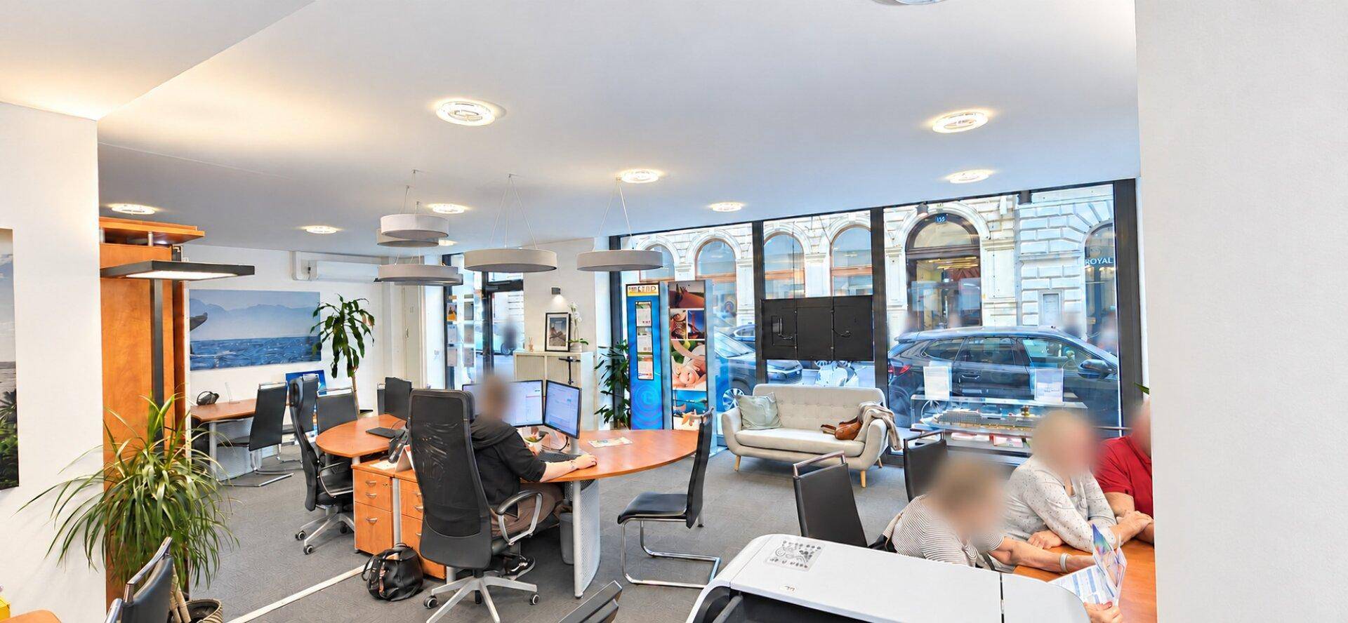 Großes, offenes Büro mit mehreren Arbeitsplätzen, Computern und Blick auf die Straße.
