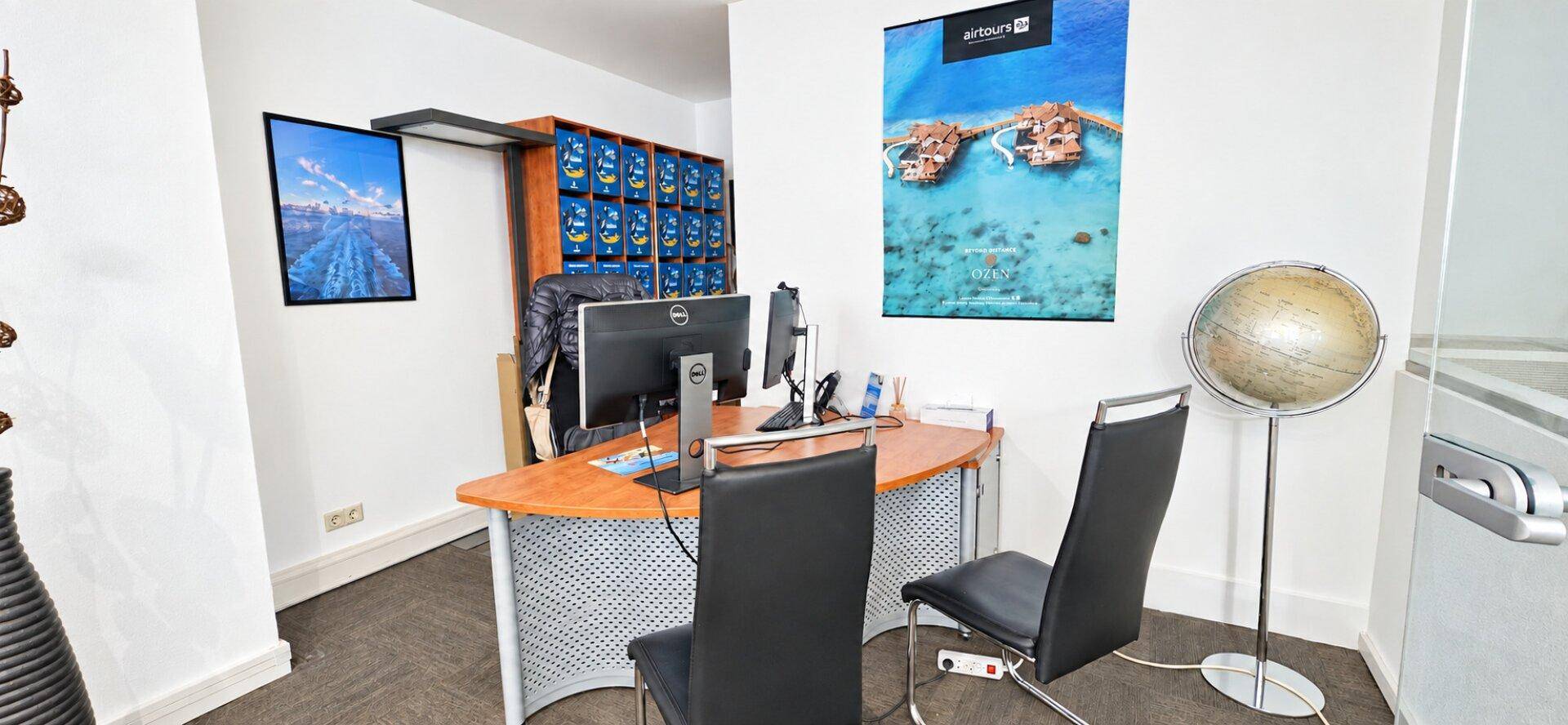 Einzelner Arbeitsplatz in einem Büro mit Schreibtisch, Computer und einem dekorativen Globus.