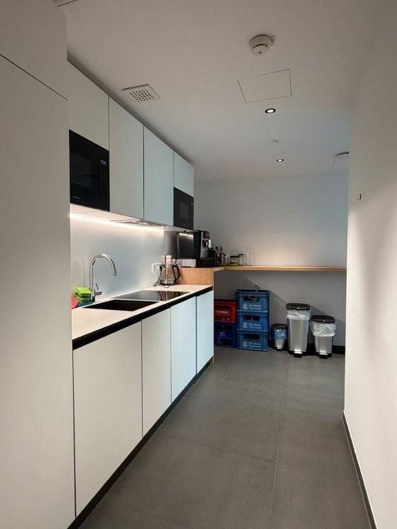 Funktionale Küchenzeile mit weißen Schränken, Spüle und integrierten Mikrowellen in einem modernen Büro.