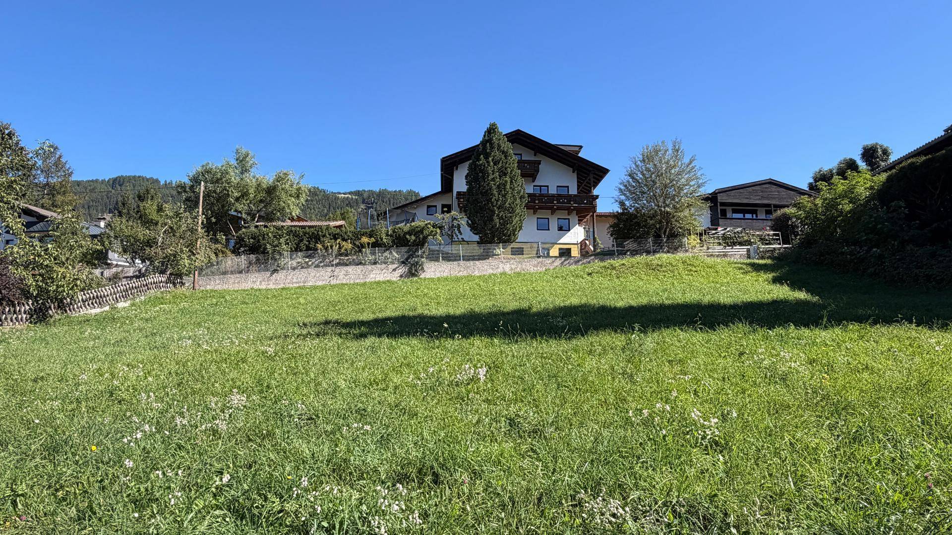 Traditionelles Haus mit Satteldach, umgeben von einer weitläufigen grünen Wiese und Bäumen.