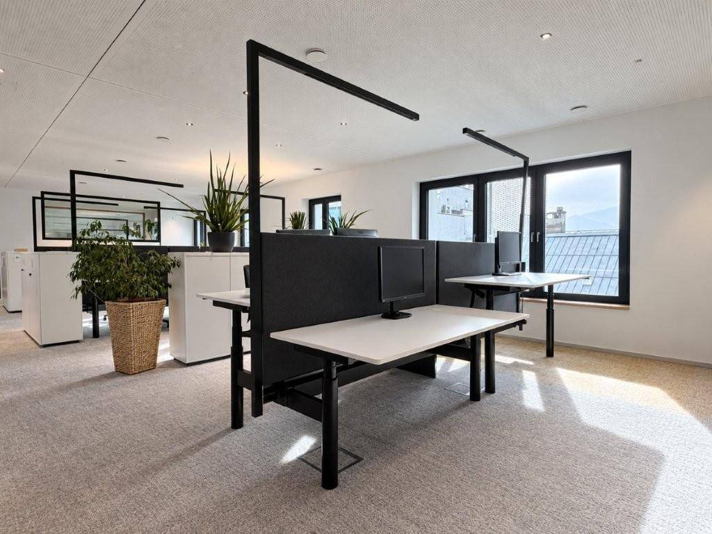 Offenes Büro mit modernen Arbeitsplätzen, Trennwänden und Blick auf die Dächer der Stadt.