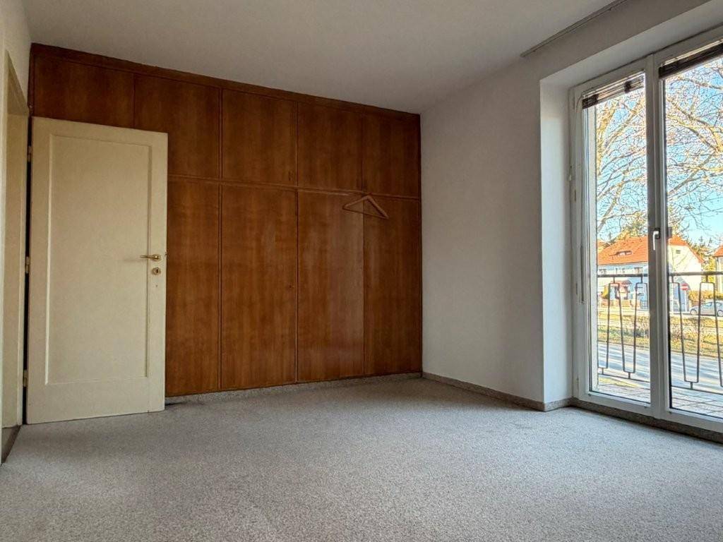 Geräumiges Schlafzimmer mit Teppichboden, Einbauschränken und Zugang zu einem Balkon.