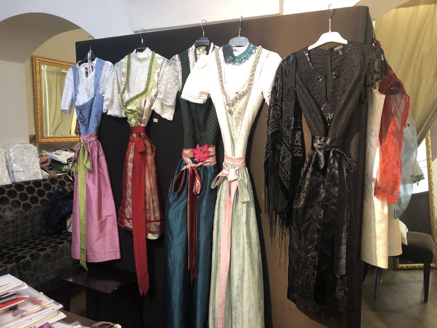 Innenansicht eines Ladens mit einer Reihe von traditionellen Dirndl-Kleidern und Trachten auf Kleiderbügeln, präsentiert in einem eleganten Ambiente.
