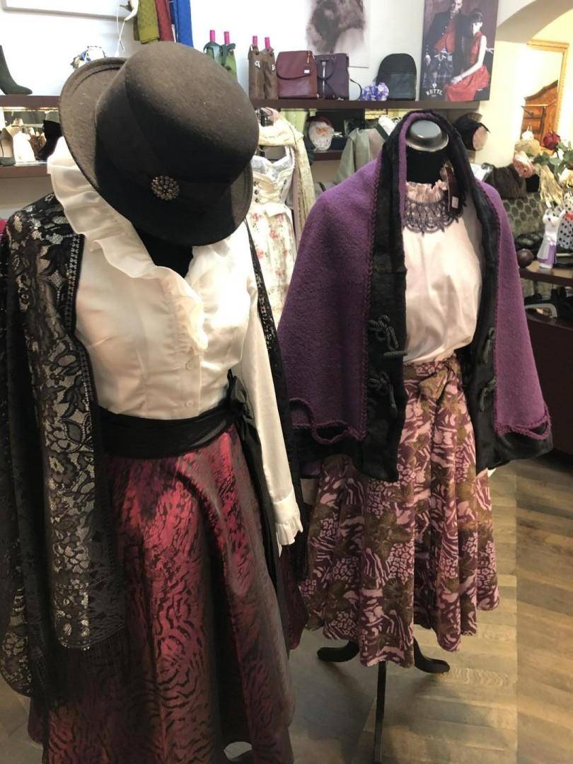 Innenansicht einer Boutique mit traditioneller Kleidung auf Schaufensterpuppen und dekorativen Elementen, die eine gehobene Atmosphäre schaffen.