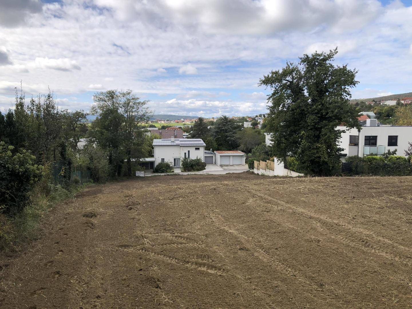 Weitläufiges Grundstück mit Blick auf die umliegende Wohnbebauung und hügelige Landschaft.
