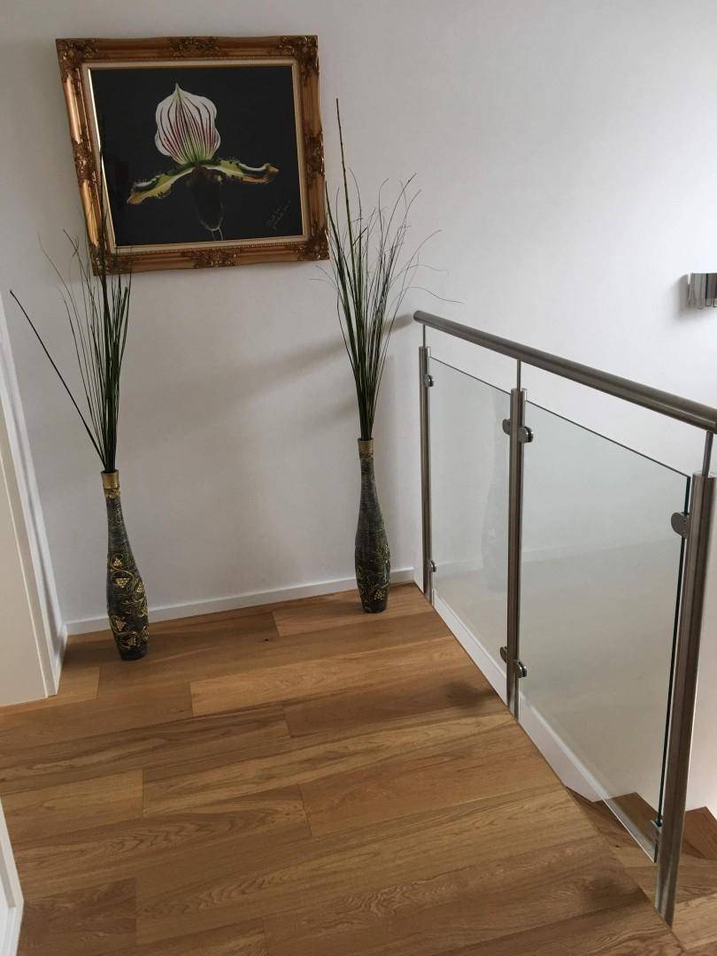 Heller Flur im Obergeschoss mit Holzboden und moderner Dekoration, Blick auf die Treppe.