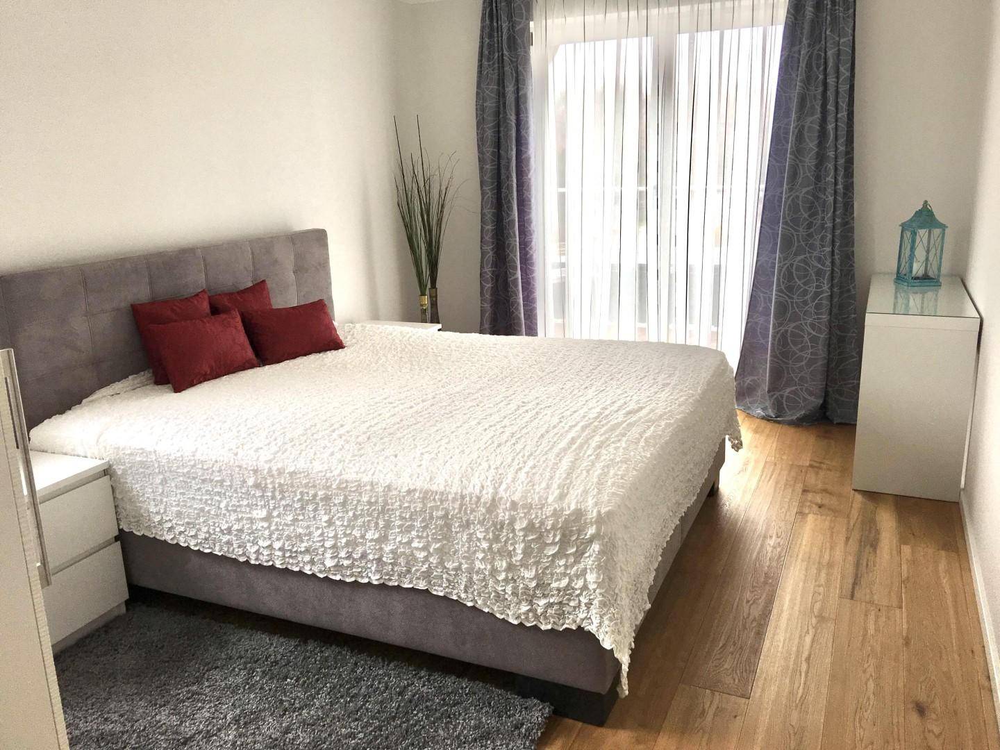 Gemütliches Schlafzimmer mit Holzboden, großem Bett und Zugang zu einem Außenbereich.