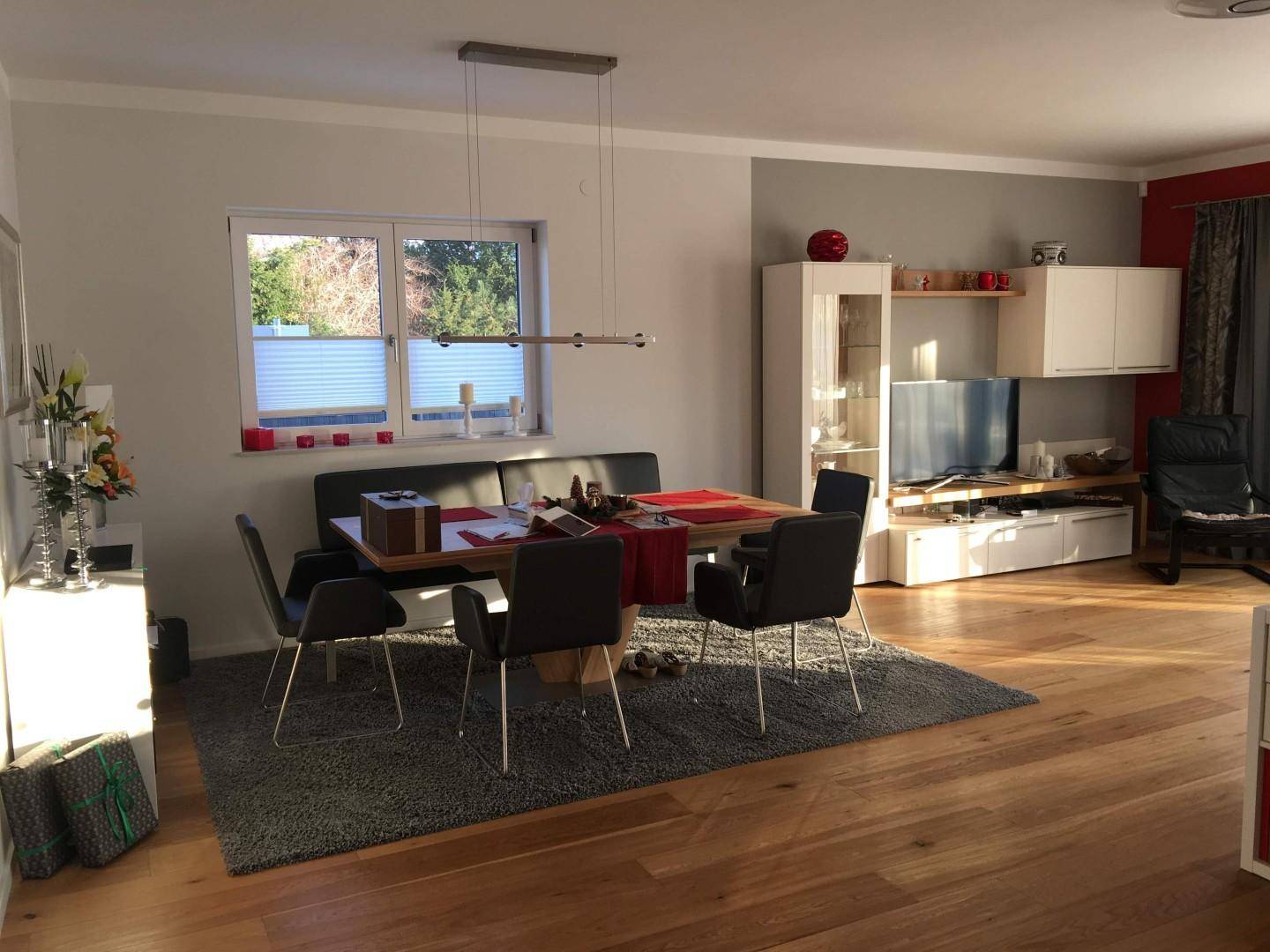 Heller Essbereich mit Holzboden und großem Fenster, offen zum Wohnbereich und modern eingerichtet.