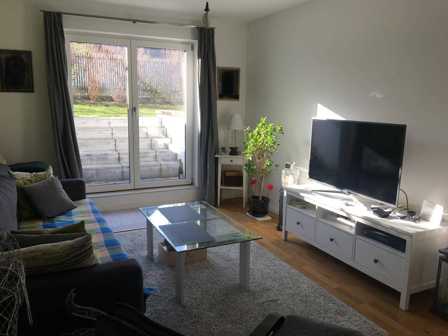 Gemütliches Wohnzimmer mit Holzboden, Sofa und Fernseher, mit direktem Zugang zum Garten.