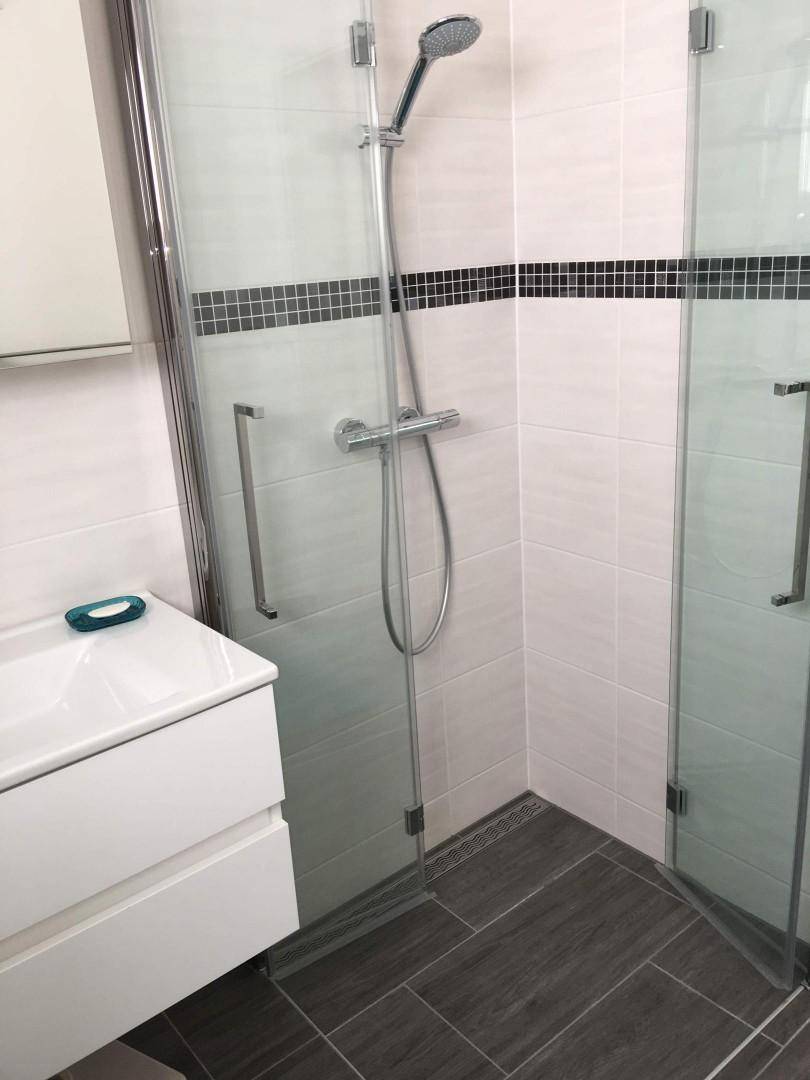 Modernes Badezimmer mit ebenerdiger Dusche und dunklen Bodenfliesen, sauber und hell.