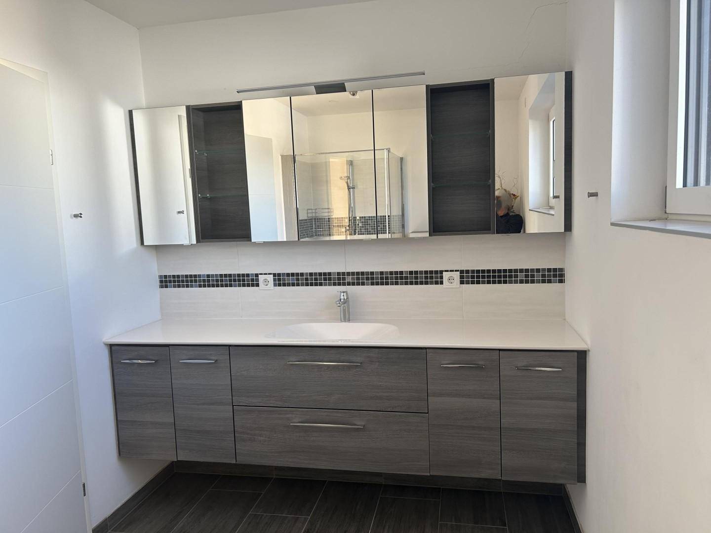 Geräumiges Badezimmer mit Doppelwaschbecken, Spiegelschrank und modernen Fliesen, hell und funktional.