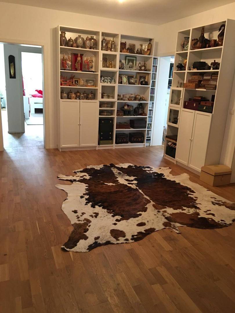 Heller Raum mit Holzboden und großen Bücherregalen, dekoriert mit verschiedenen Objekten.