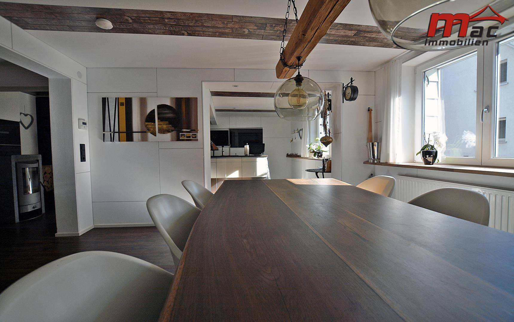 Essbereich mit Holztisch und Deckenbalken, verbunden mit der Küche.