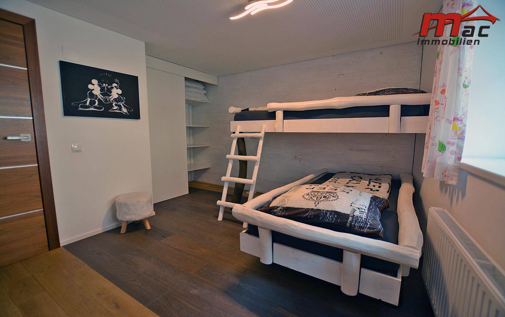 Gemütliches Kinderzimmer mit Etagenbett und integrierten Regalen.