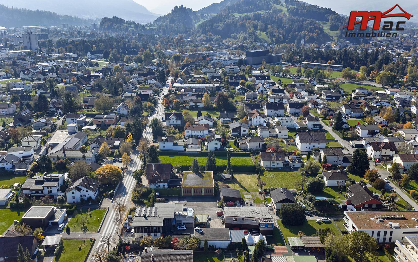 Weitläufige Luftaufnahme der Wohnsiedlung mit Blick auf die umliegende Berglandschaft und Wälder.