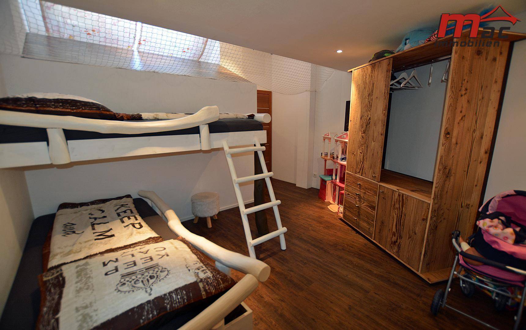 Kinderzimmer mit Etagenbett, Holzschrank und Spielzeug im Dachgeschoss.