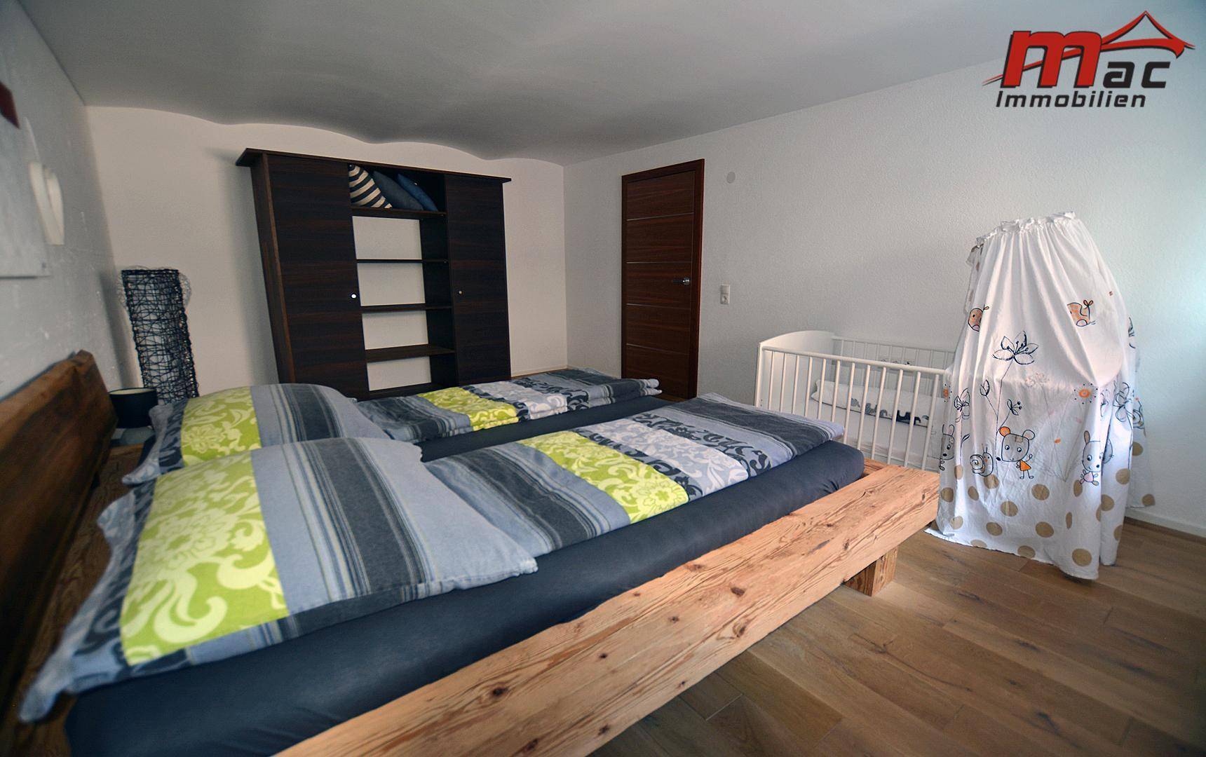 Geräumiges Schlafzimmer mit Holzbett, Kleiderschrank und Kinderbett.