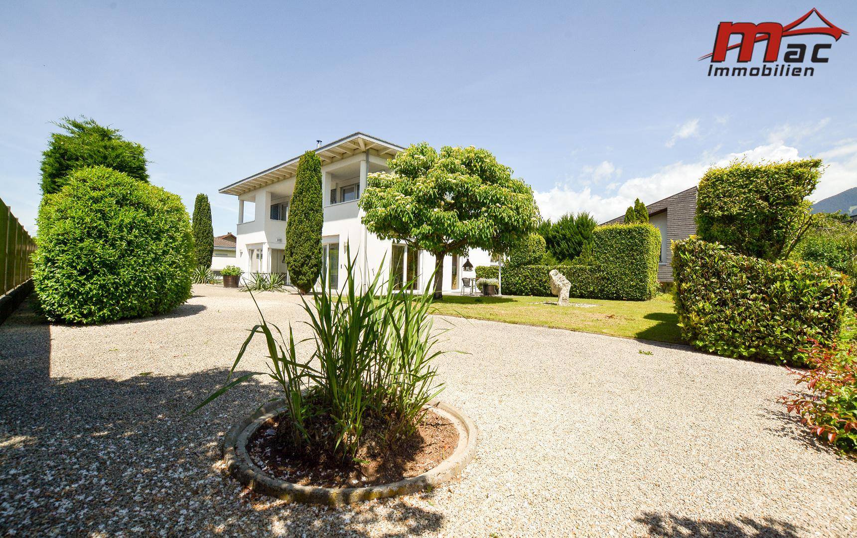 Weitläufiger Vorgarten mit Kiesflächen und einem modernen Einfamilienhaus im Hintergrund.