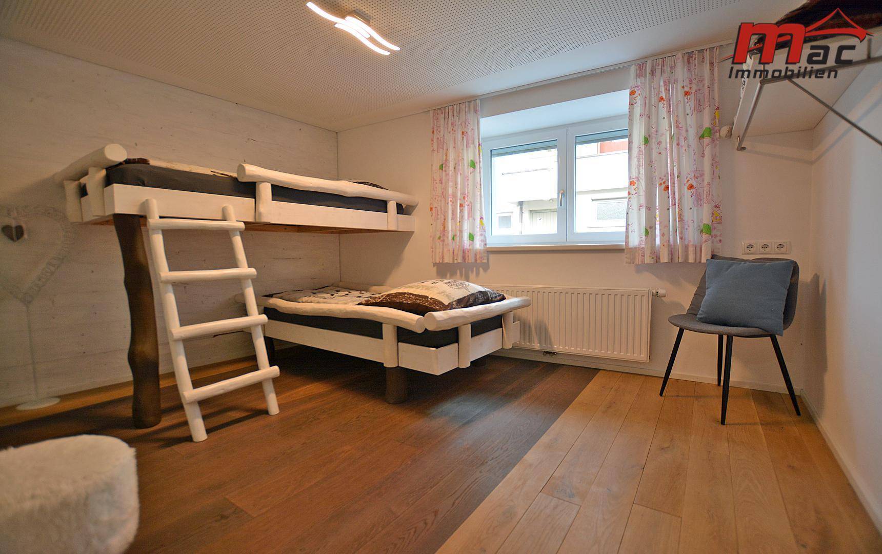 Kinderzimmer mit Etagenbett und Holzboden, hell und freundlich gestaltet.