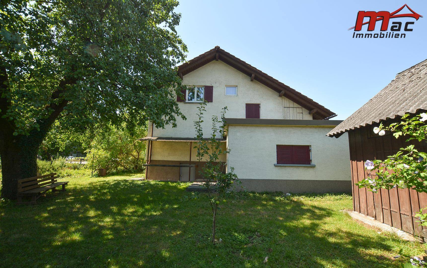 Rückansicht des Hauses mit einem kleinen Schuppen und einem schattigen Gartenbereich.