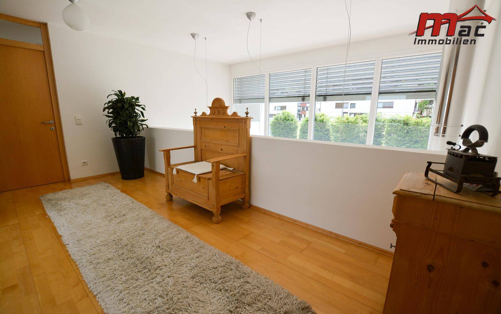 Heller Galeriebereich im Obergeschoss mit Holzboden, traditioneller Sitzbank und Fenster.