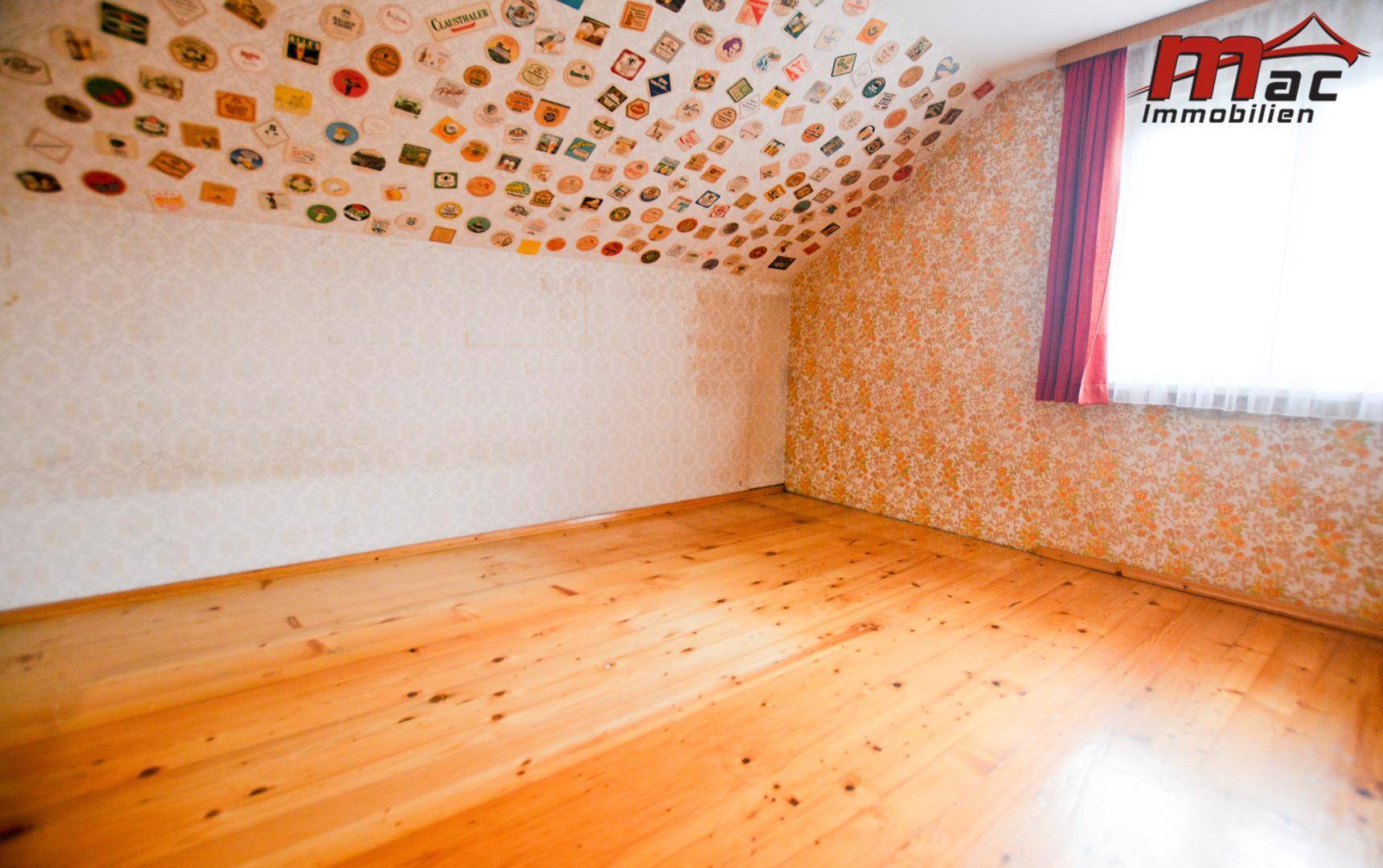 Dachgeschosszimmer mit Holzboden, schräger Decke und einzigartiger Sticker-Dekoration.