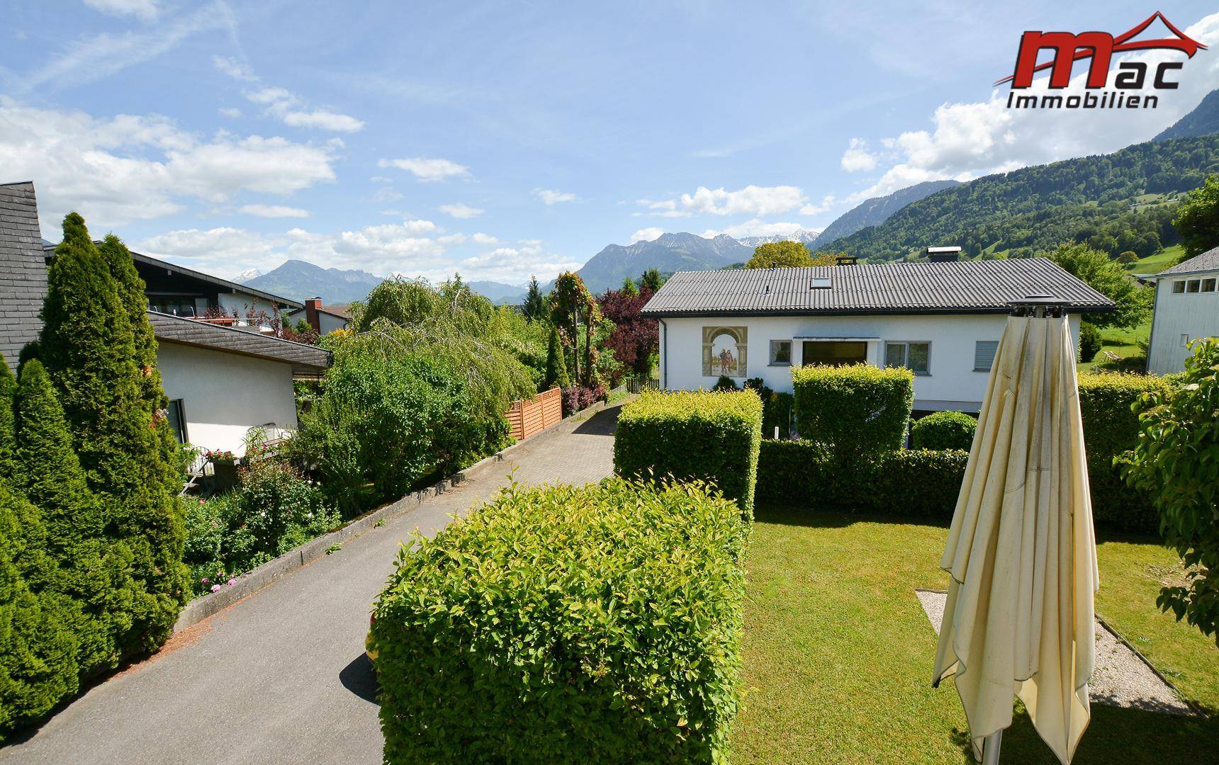 Weitläufige Ansicht des Anwesens mit gepflegtem Garten und umliegender Berglandschaft.