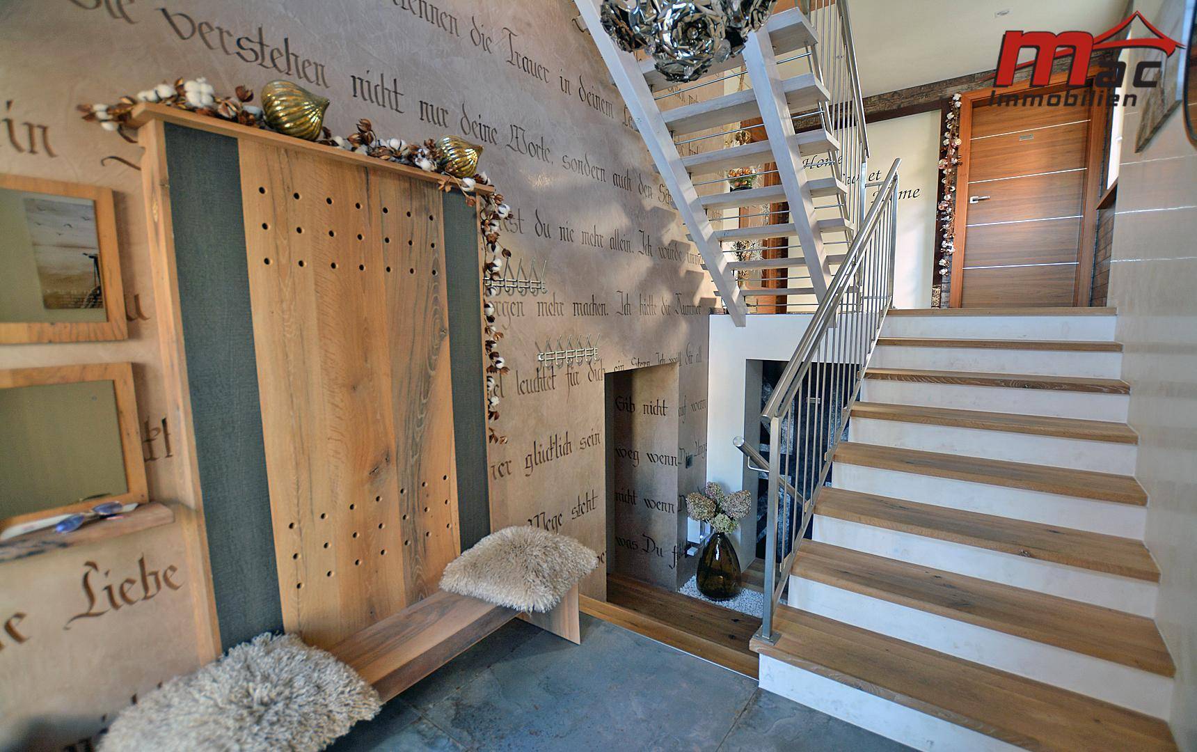 Geräumiger Flur mit Holztreppe und dekorativer Wandbeschriftung.