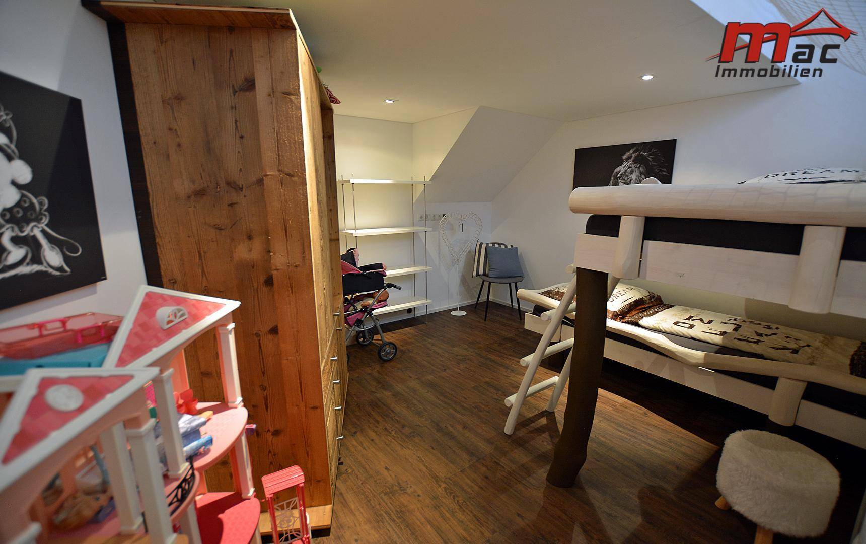 Kinderzimmer im Dachgeschoss mit Etagenbett, Holzschrank und Stauraum.