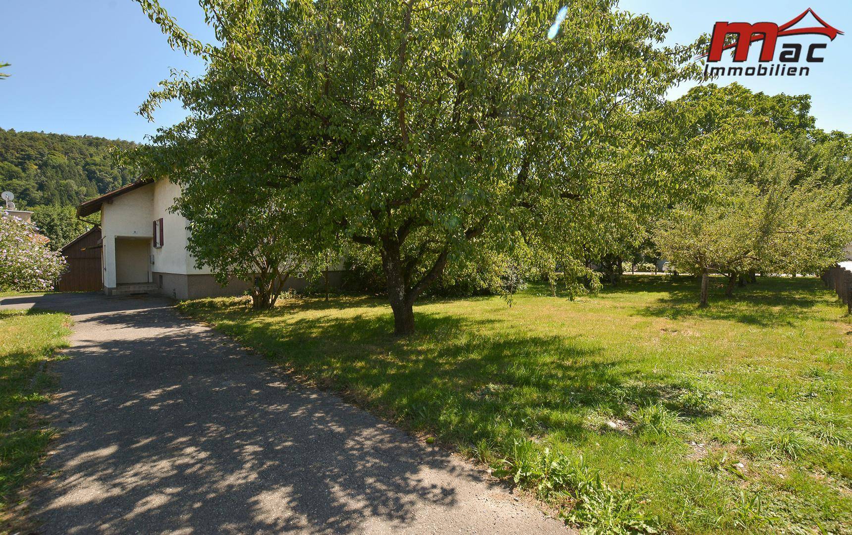 Weitläufiger Garten mit Rasenfläche, Bäumen und einem Weg, der zum Haus führt.